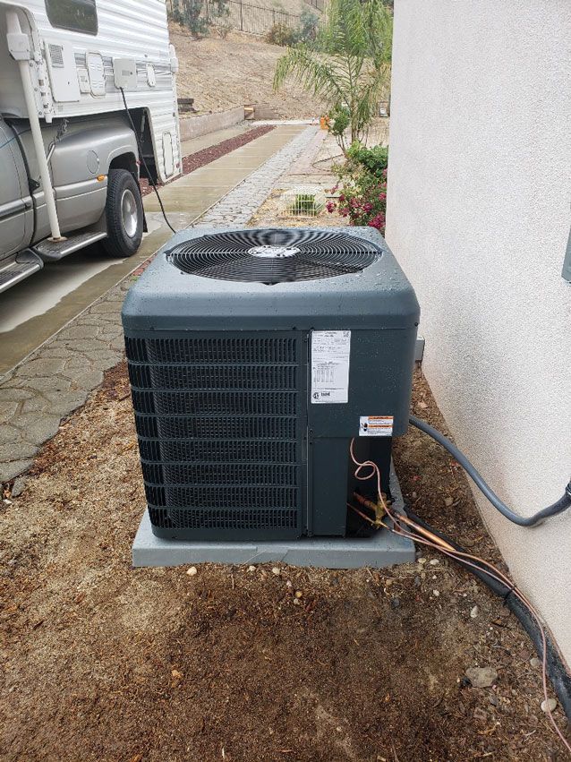 An air conditioner is sitting on the side of a building next to a truck.