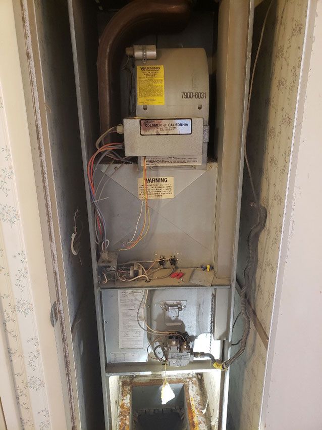 A dirty air conditioner is sitting in a corner of a room.