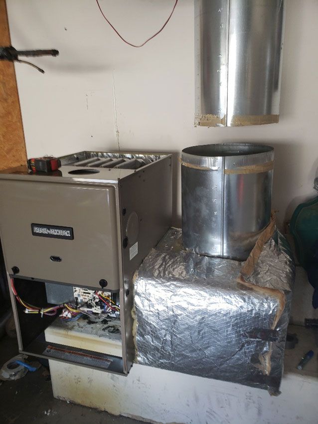 A furnace is sitting in a garage next to a wall.