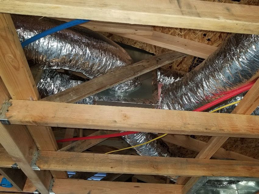 A wooden structure with aluminum ducts and wires coming out of it.