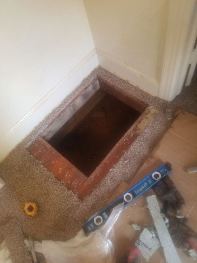 A room with a hole in the floor and a level on the floor.