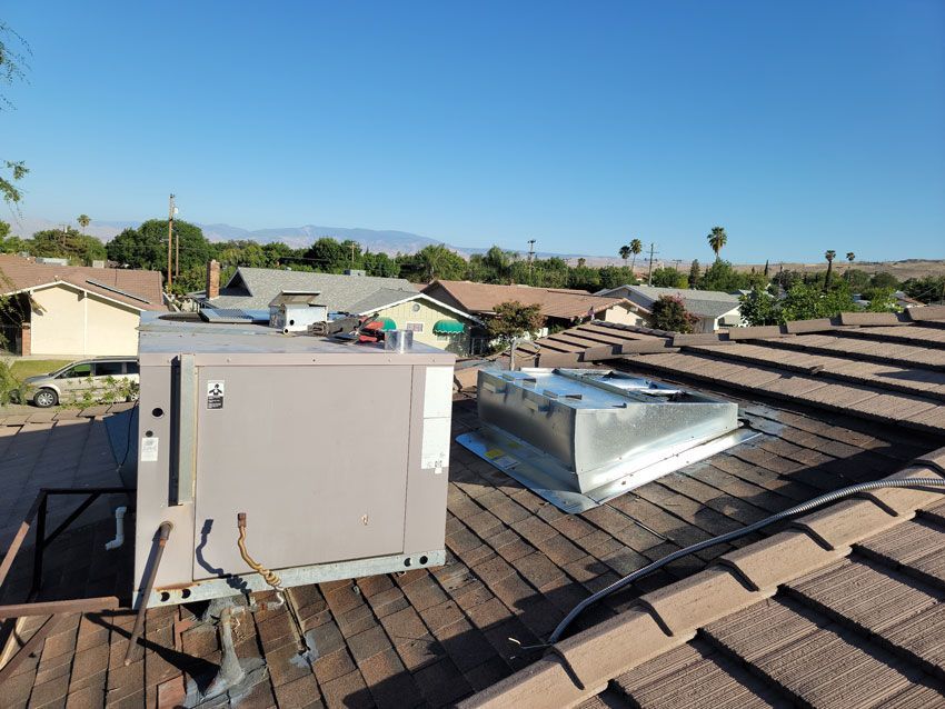 There are two air conditioners on the roof of a house.