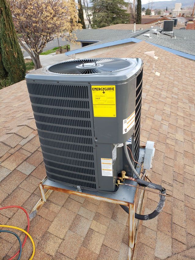 A large air conditioner is sitting on top of a brick roof.
