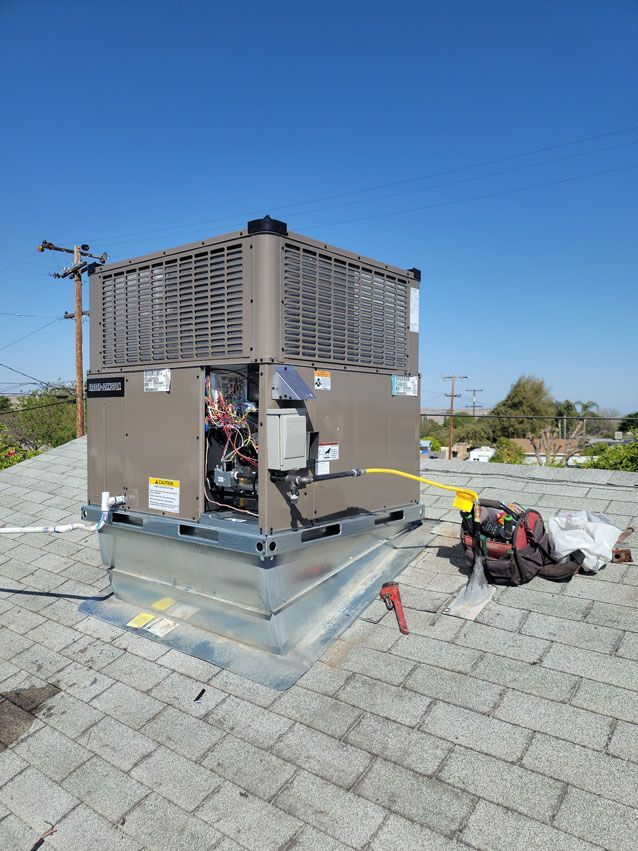 A large air conditioner is sitting on top of a brick roof.