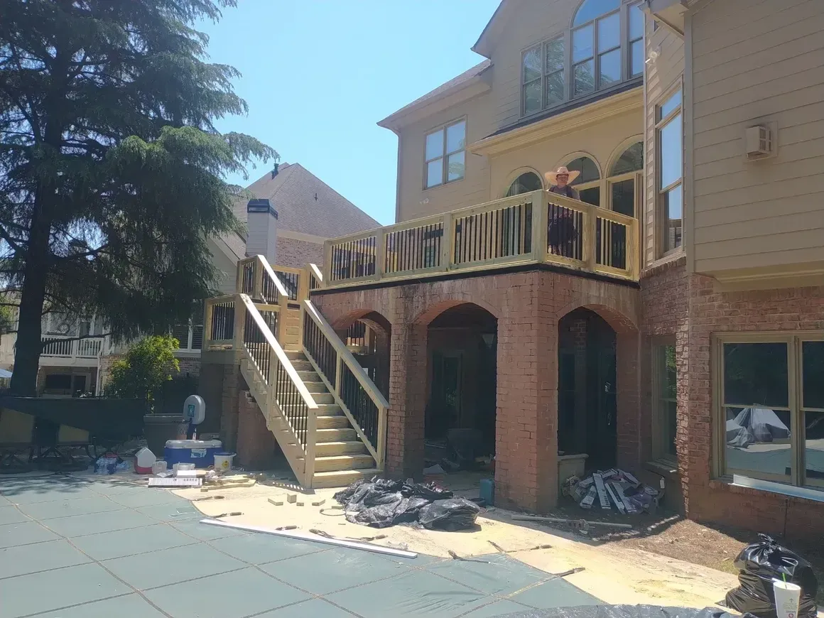 A two-story house with a partially built wooden deck and brick arches; construction is in progress.
