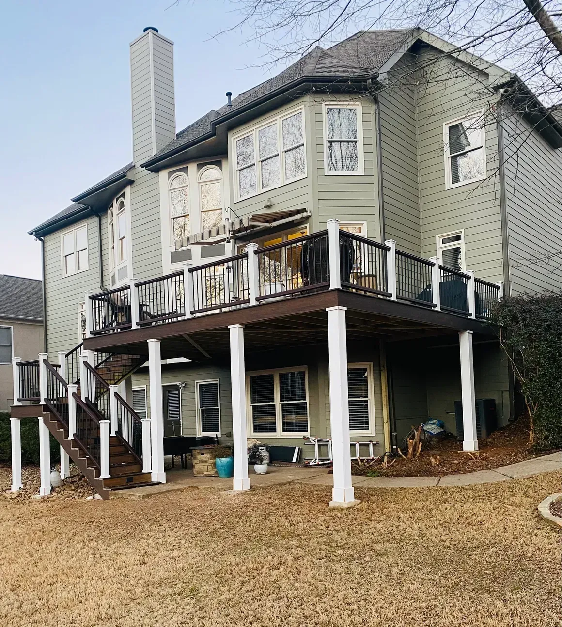 Back view of a multi-story house with two decks and white support columns.