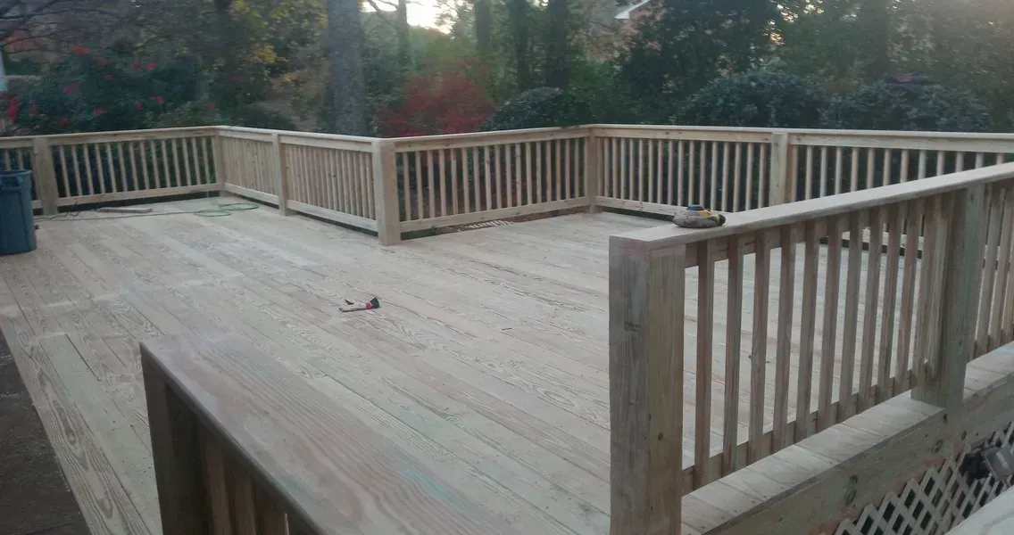 Wooden deck with railings in a backyard setting.