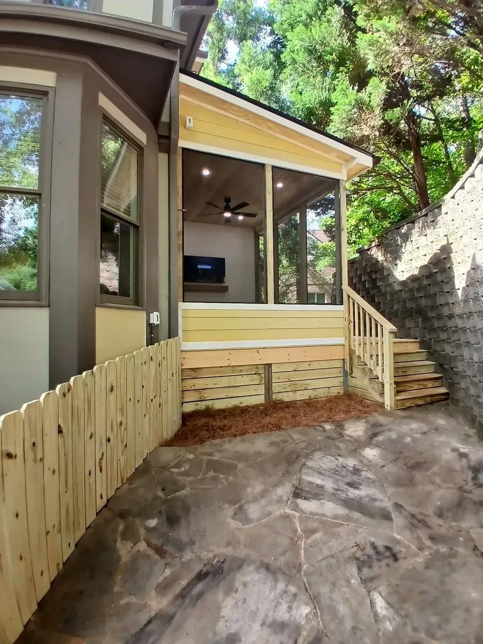 Screened porch with steps, a fence, and a stone wall.