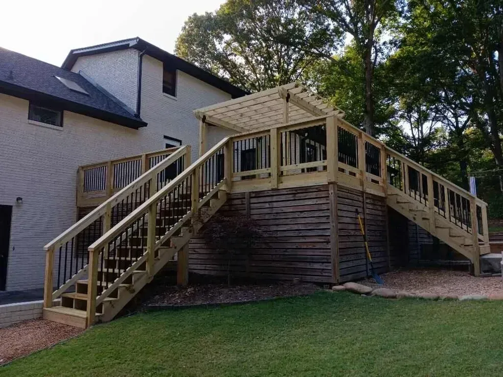 Wooden deck attached to a two-story house with stairs, a pergola, and latticework.