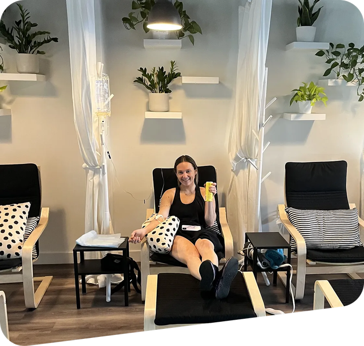 Woman relaxing in a spa chair, holding a drink, with white curtains and black chairs around her