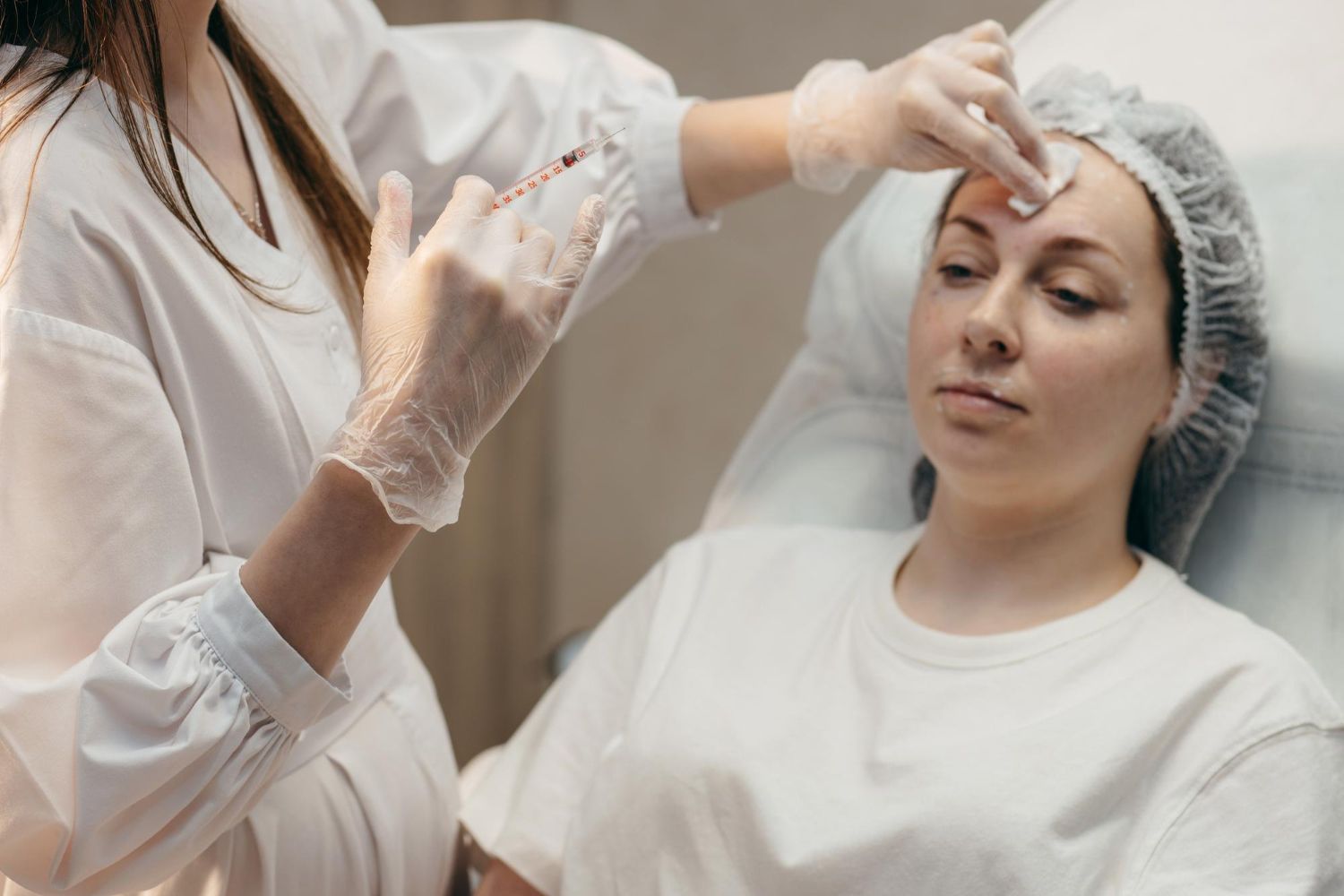 A woman is getting a botox injection on her forehead.