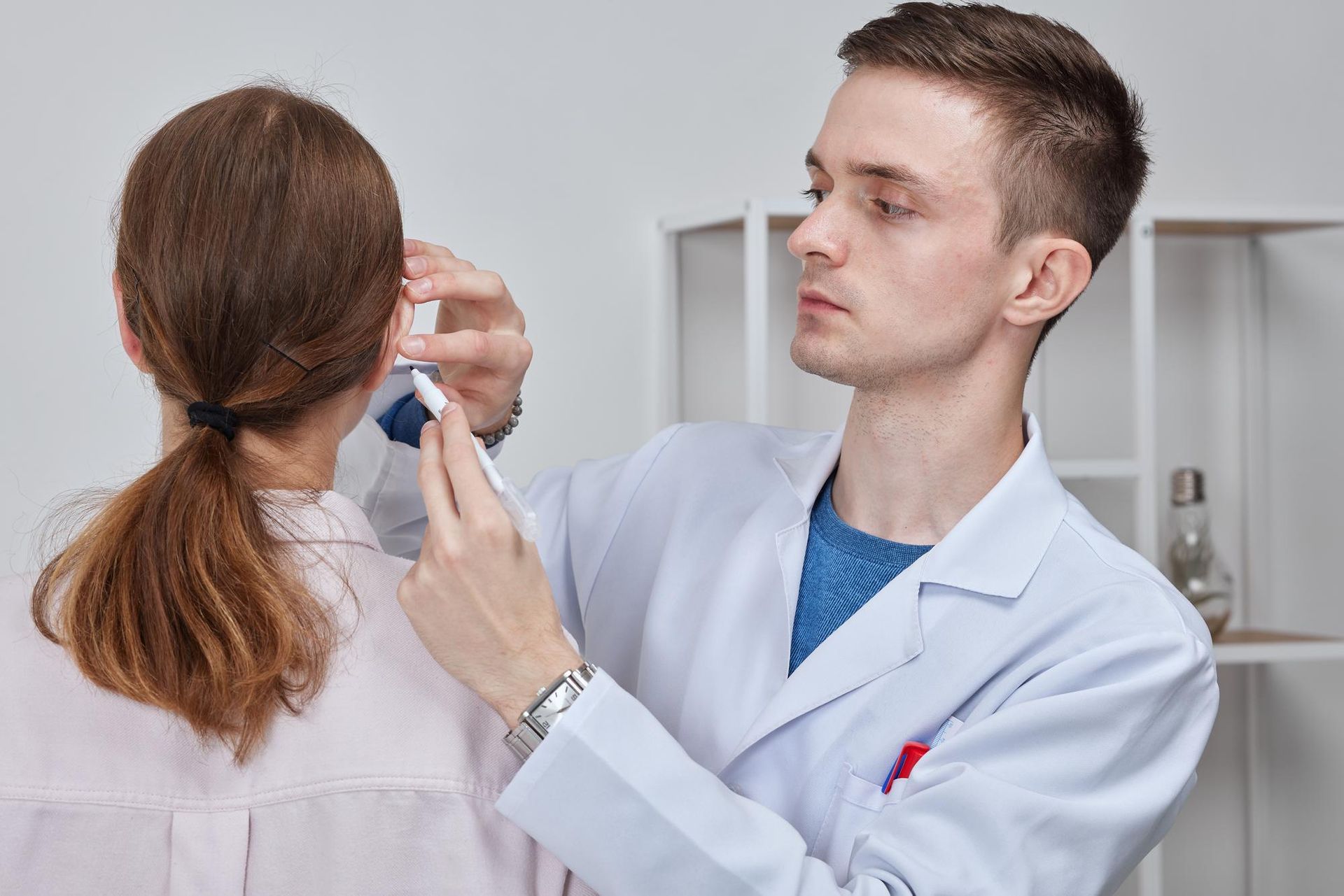 A doctor is examining a woman 's ear with a syringe.