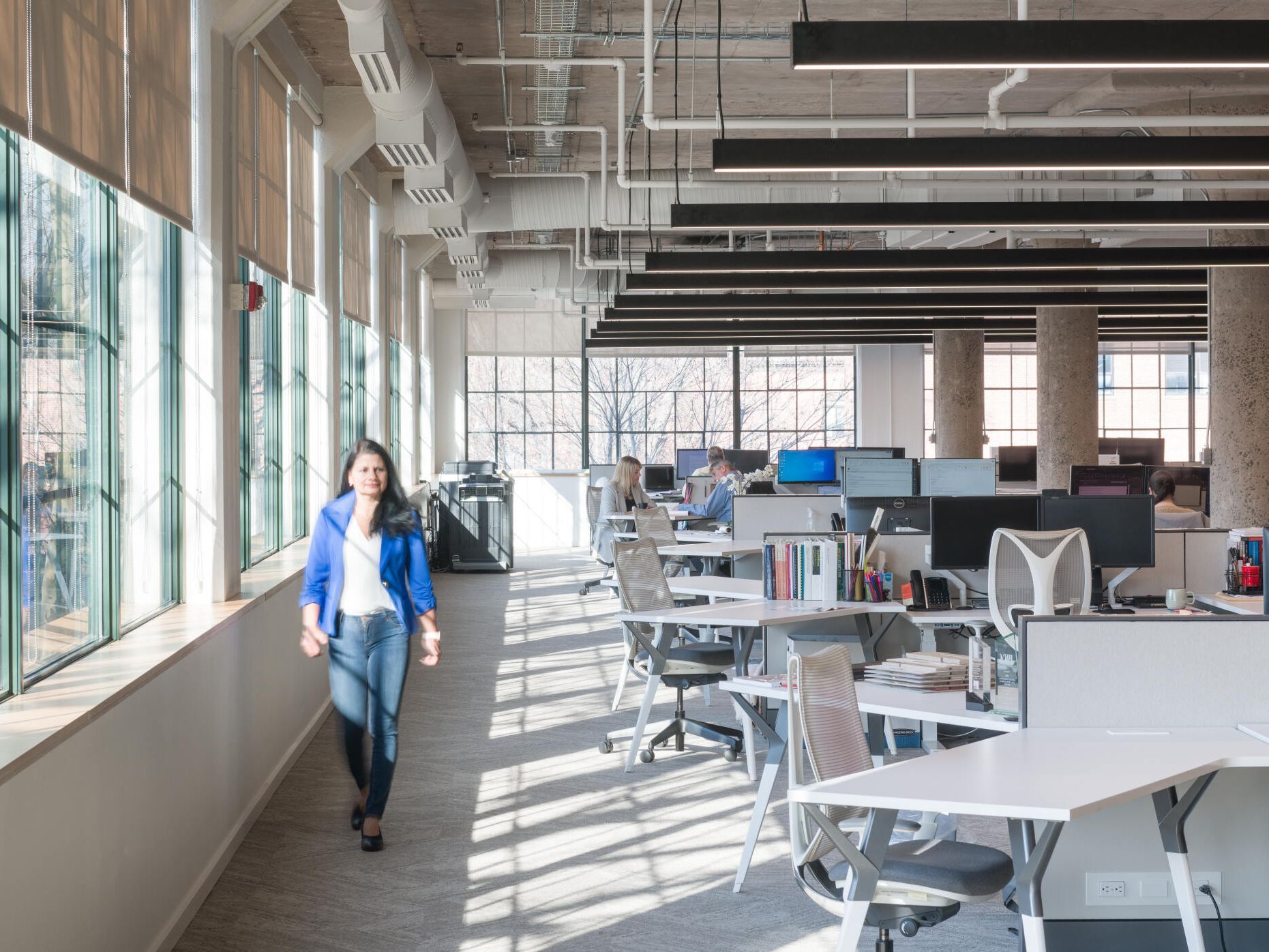 A woman is walking down a hallway in an office.