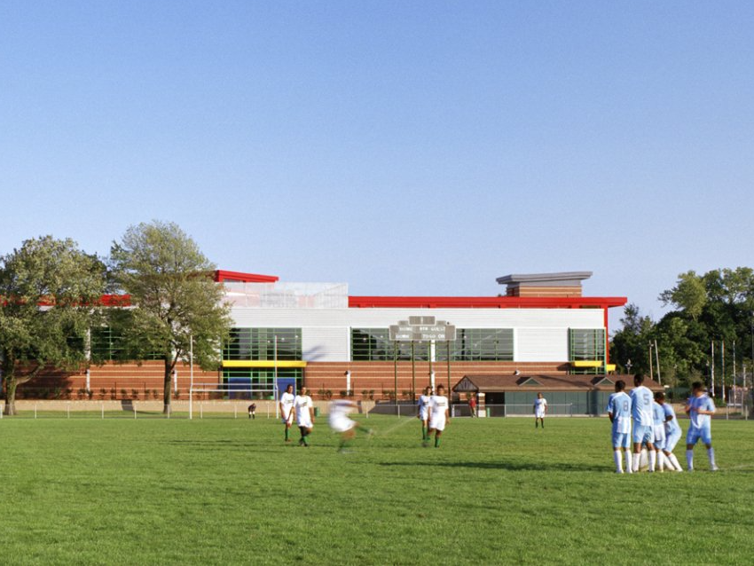 A group of people are playing soccer in front of a large building