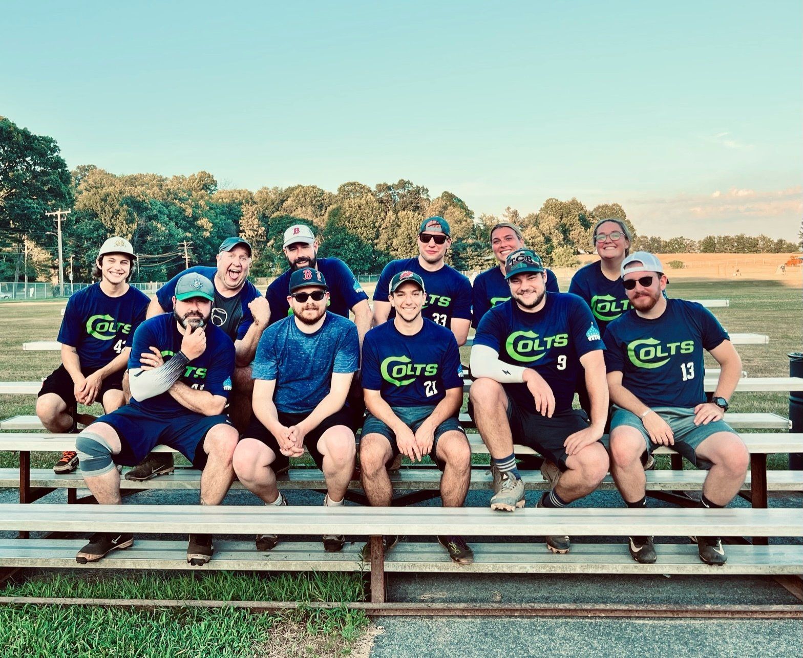 A group of men are sitting on a bench wearing colts shirts.