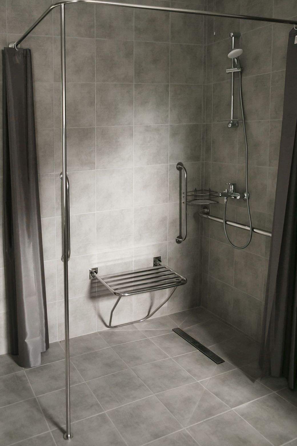 A black and white photo of a walk in shower with a bench.