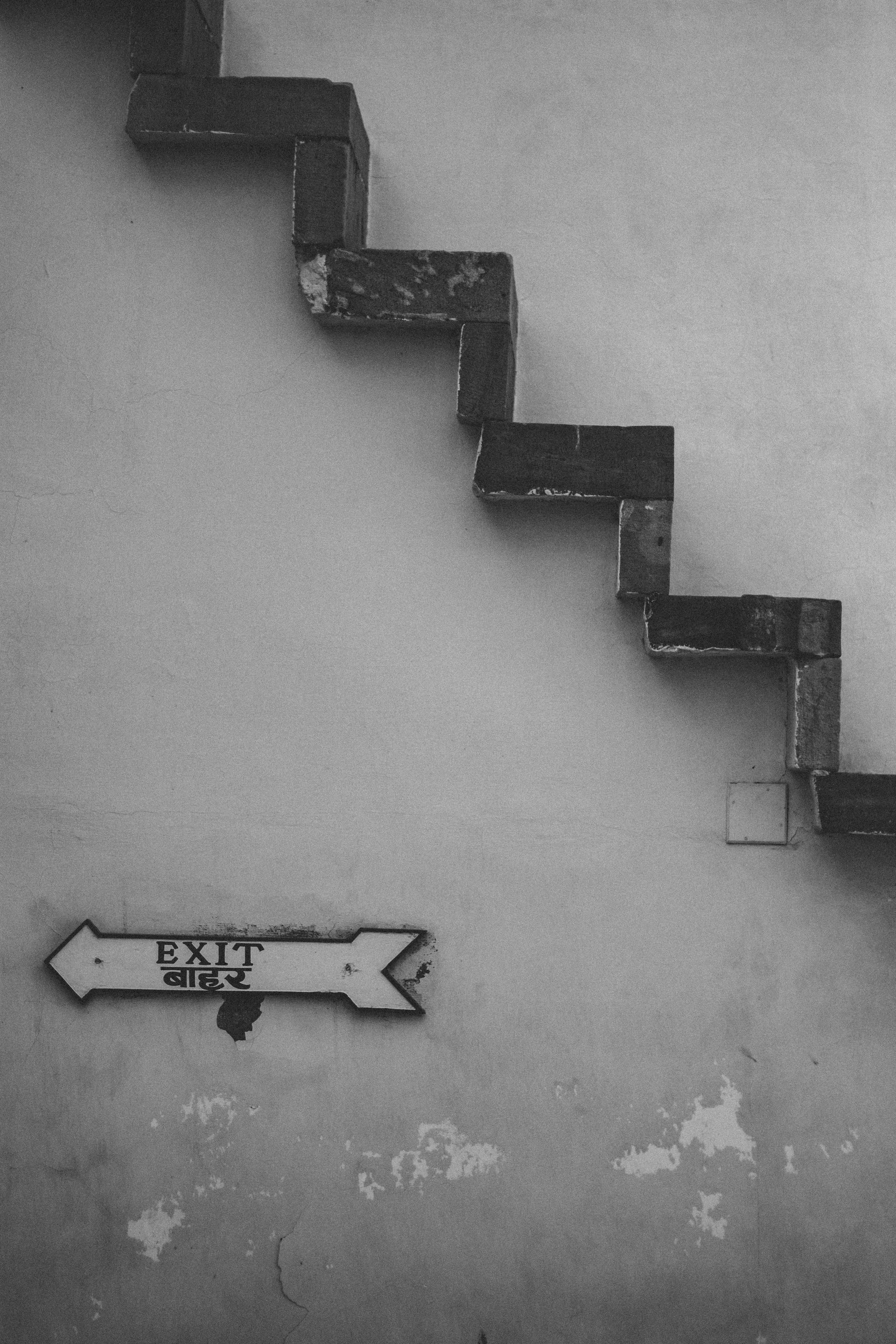 A black and white photo of stairs and an exit sign