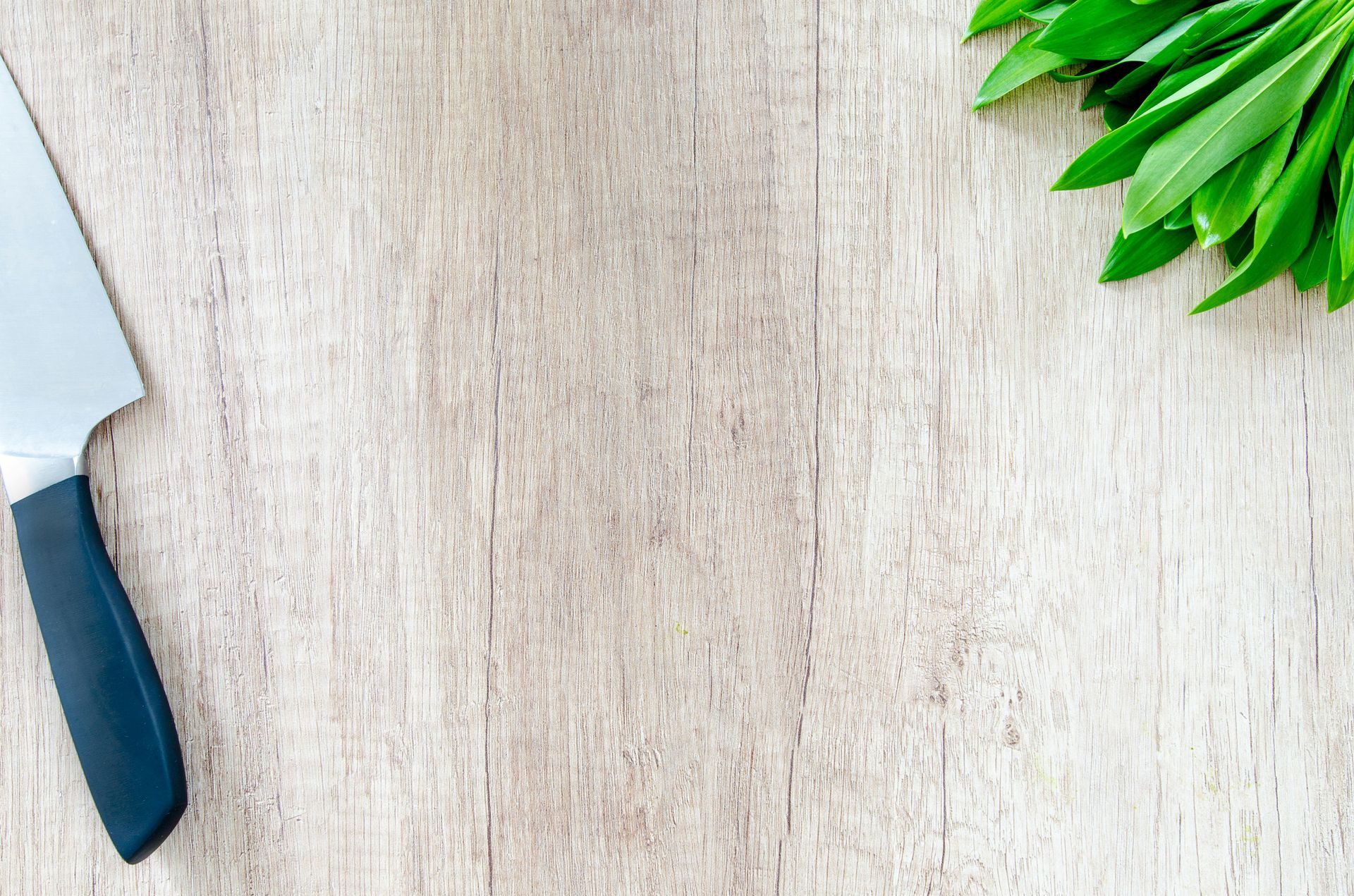 wood background with knife and greens