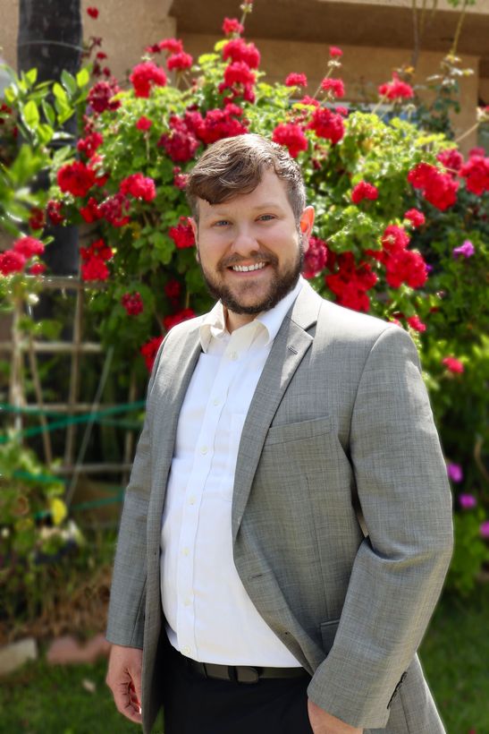 Reagan Wallace, REALTOR Real Estate Agent in Los Angeles standing in front of a home with several blooming flowers