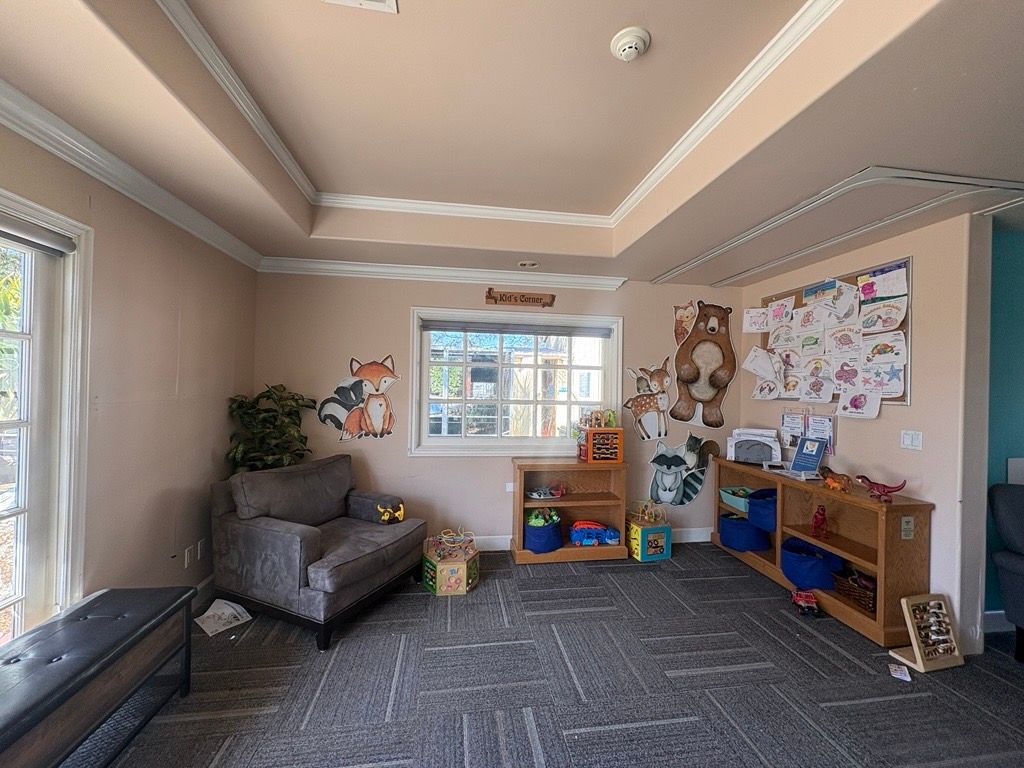 Child's playroom: blue table and chairs, books, toys, and a window with natural light.