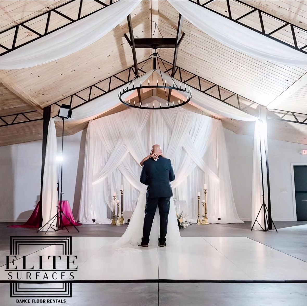 A man in a suit stands in front of a bride in a white dress