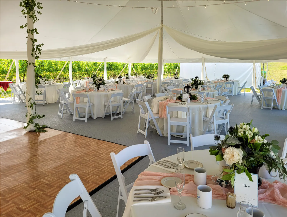 A large tent with tables and chairs set up for a wedding reception.