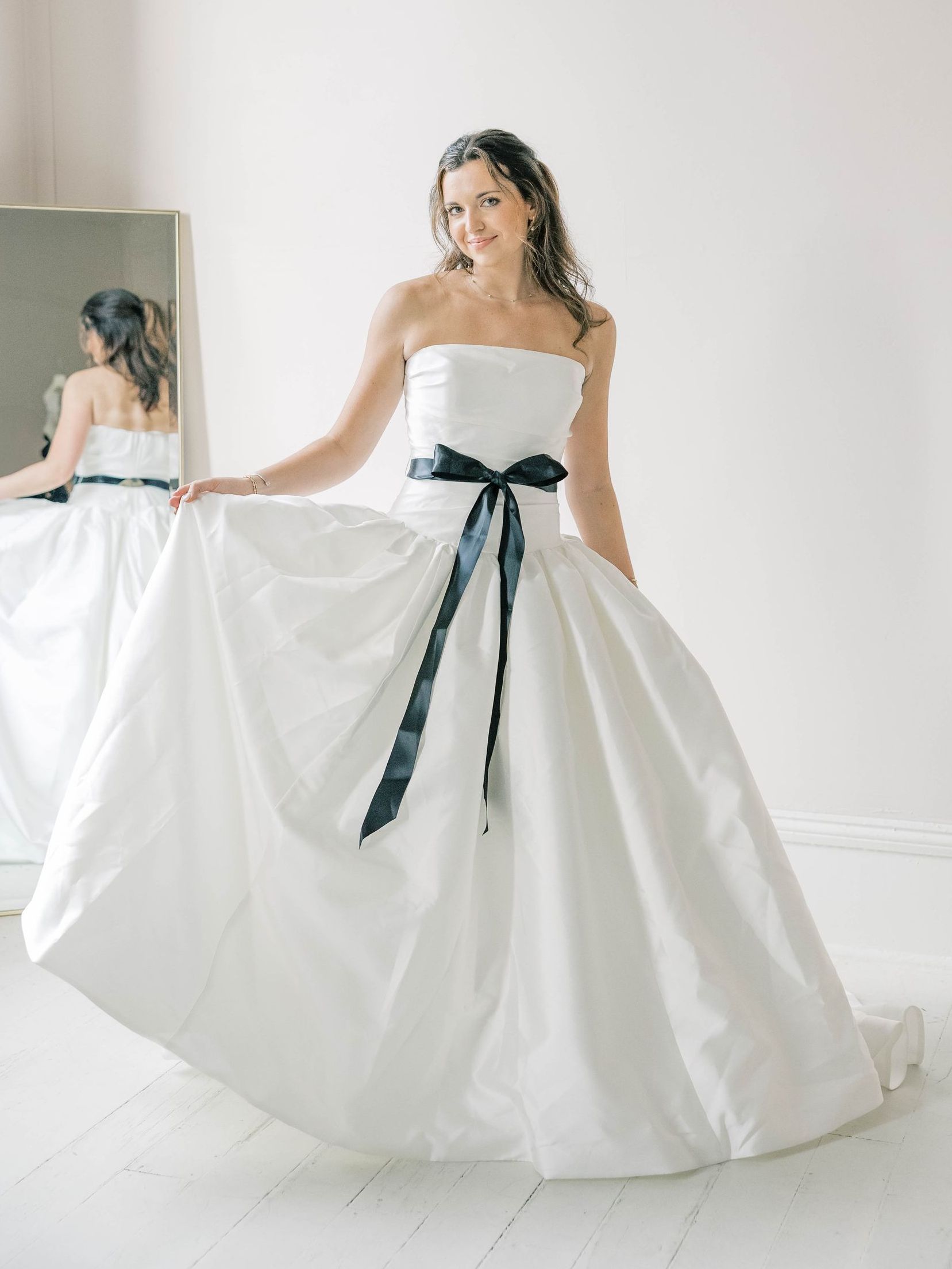 A woman in a white wedding dress is standing in a room.