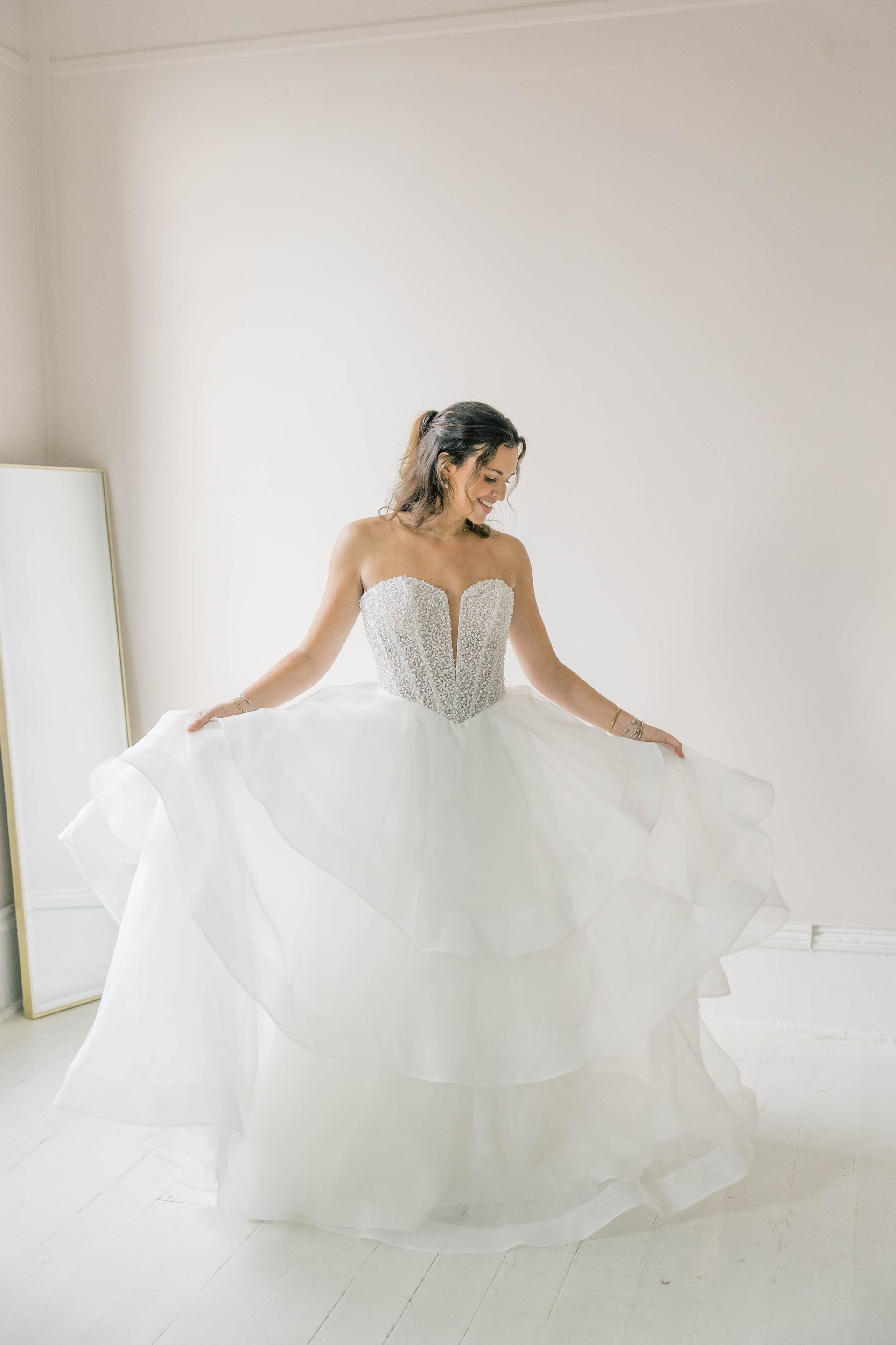 A woman in a white wedding dress is standing in front of a vase of flowers.