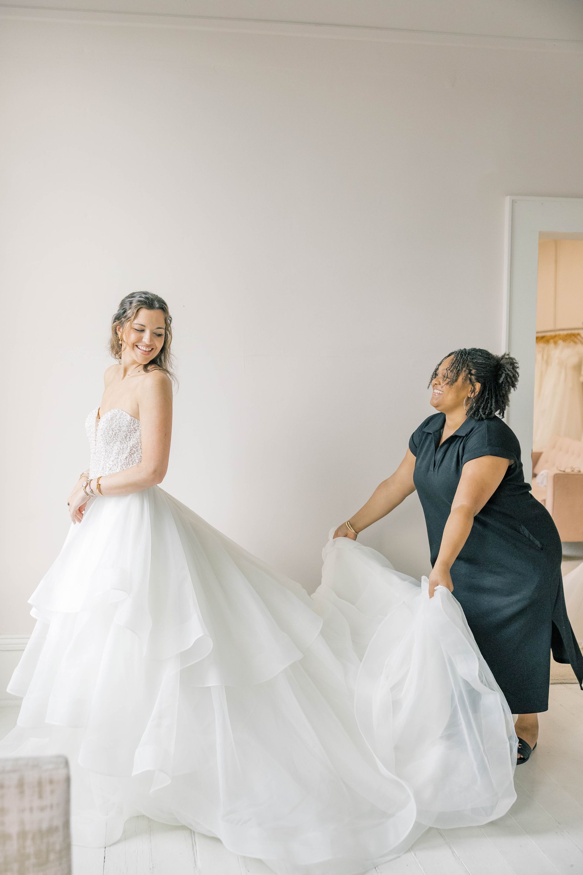 A woman in a white wedding dress is standing in front of a mirror.