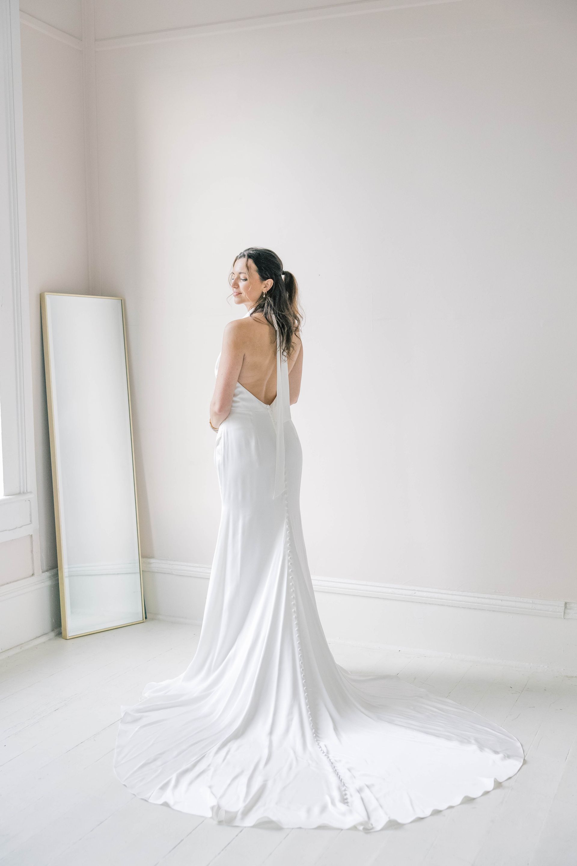 A woman in a wedding dress is sitting on a couch in a room.
