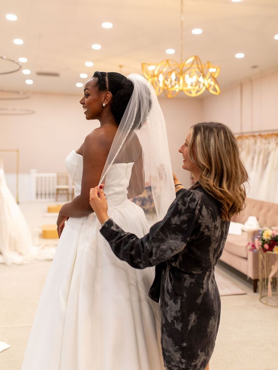 A woman is helping a woman in a wedding dress with her veil.
