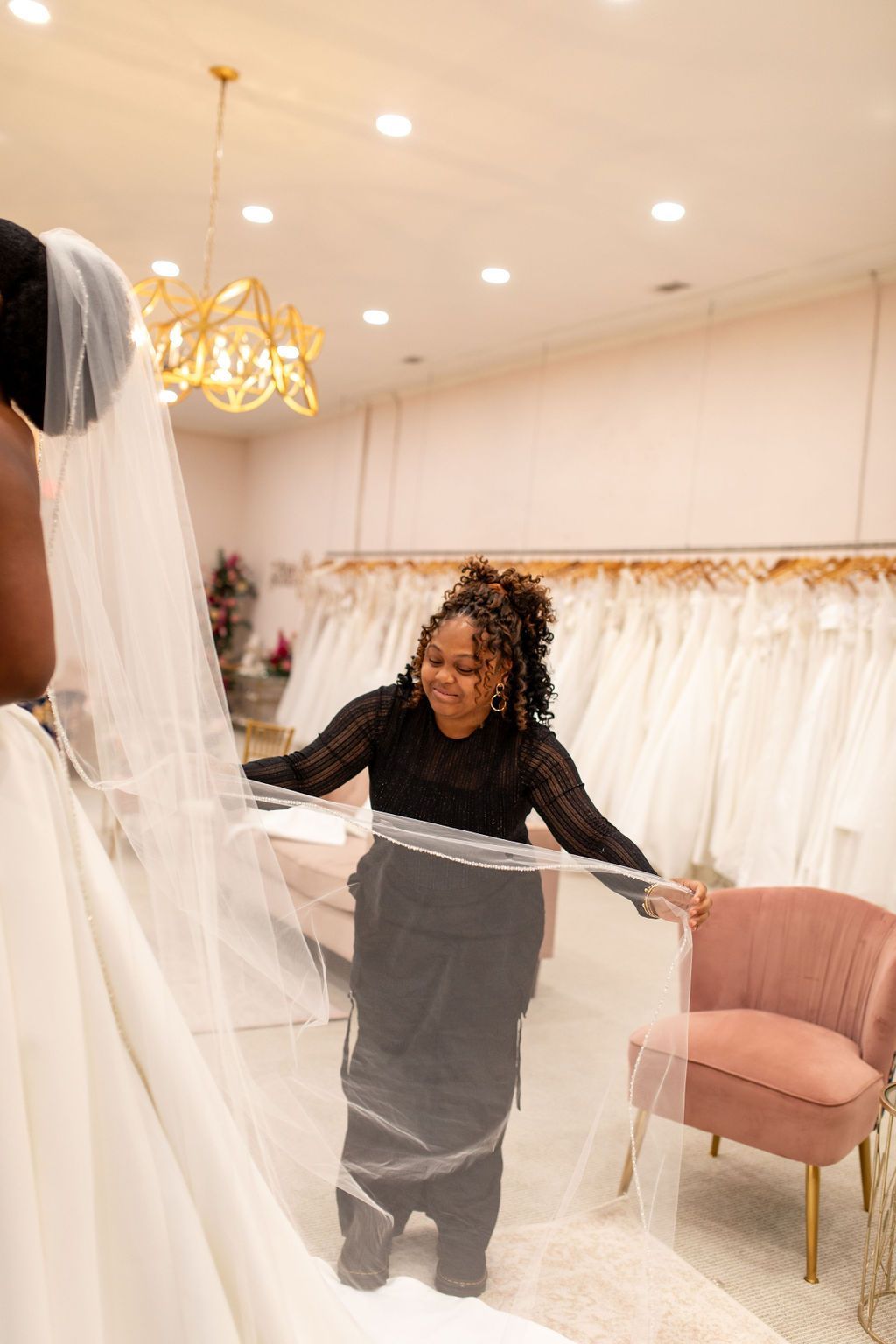 A woman in a wedding dress is holding a veil in a bridal shop.