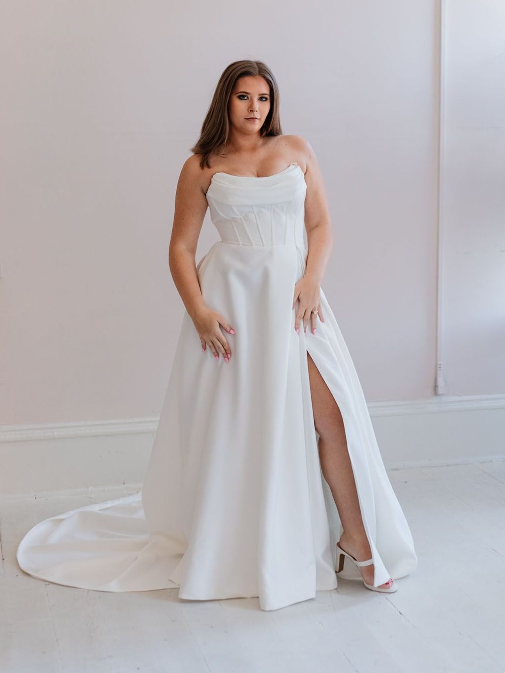 A woman is wearing a white wedding dress with a high slit.