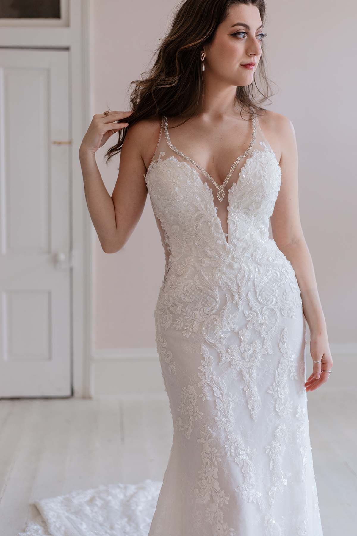 A woman in a white wedding dress is standing in a room.