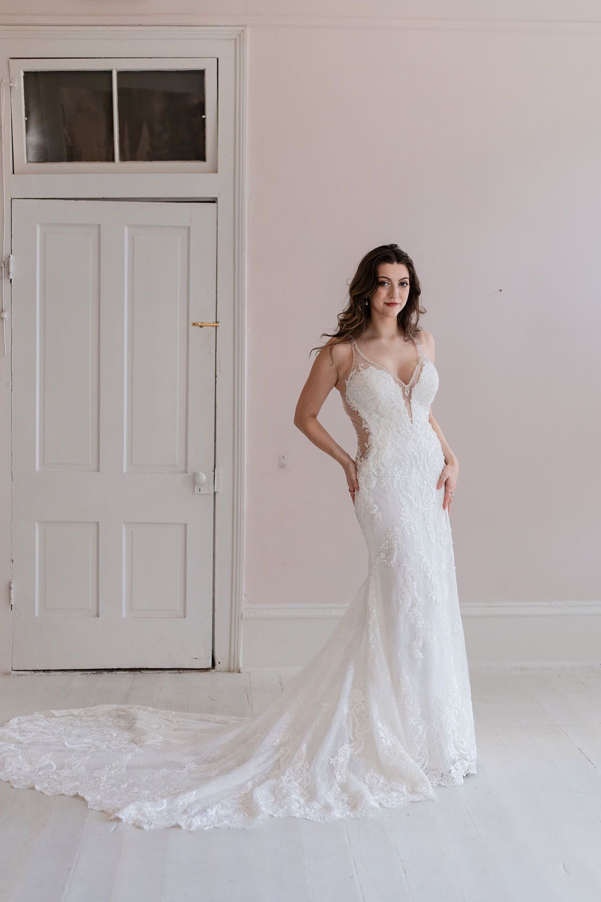 A woman in a wedding dress is standing in front of a white door.