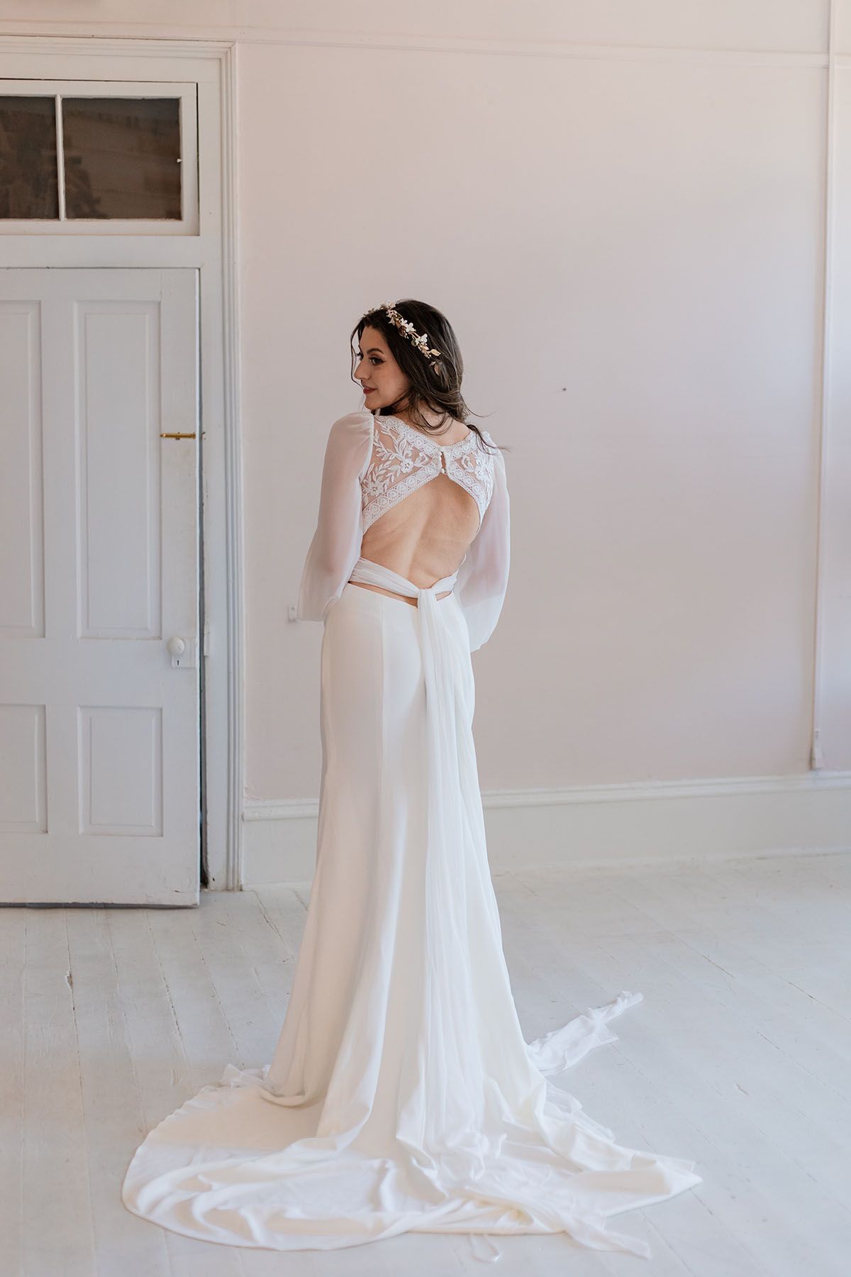 A woman in a white wedding dress is standing in a room.
