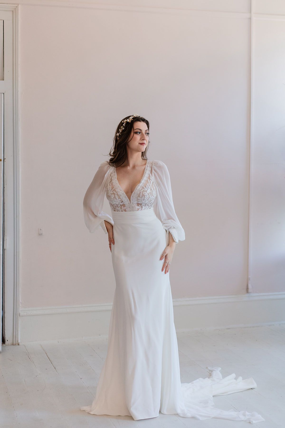 A woman in a white wedding dress is standing in a room.