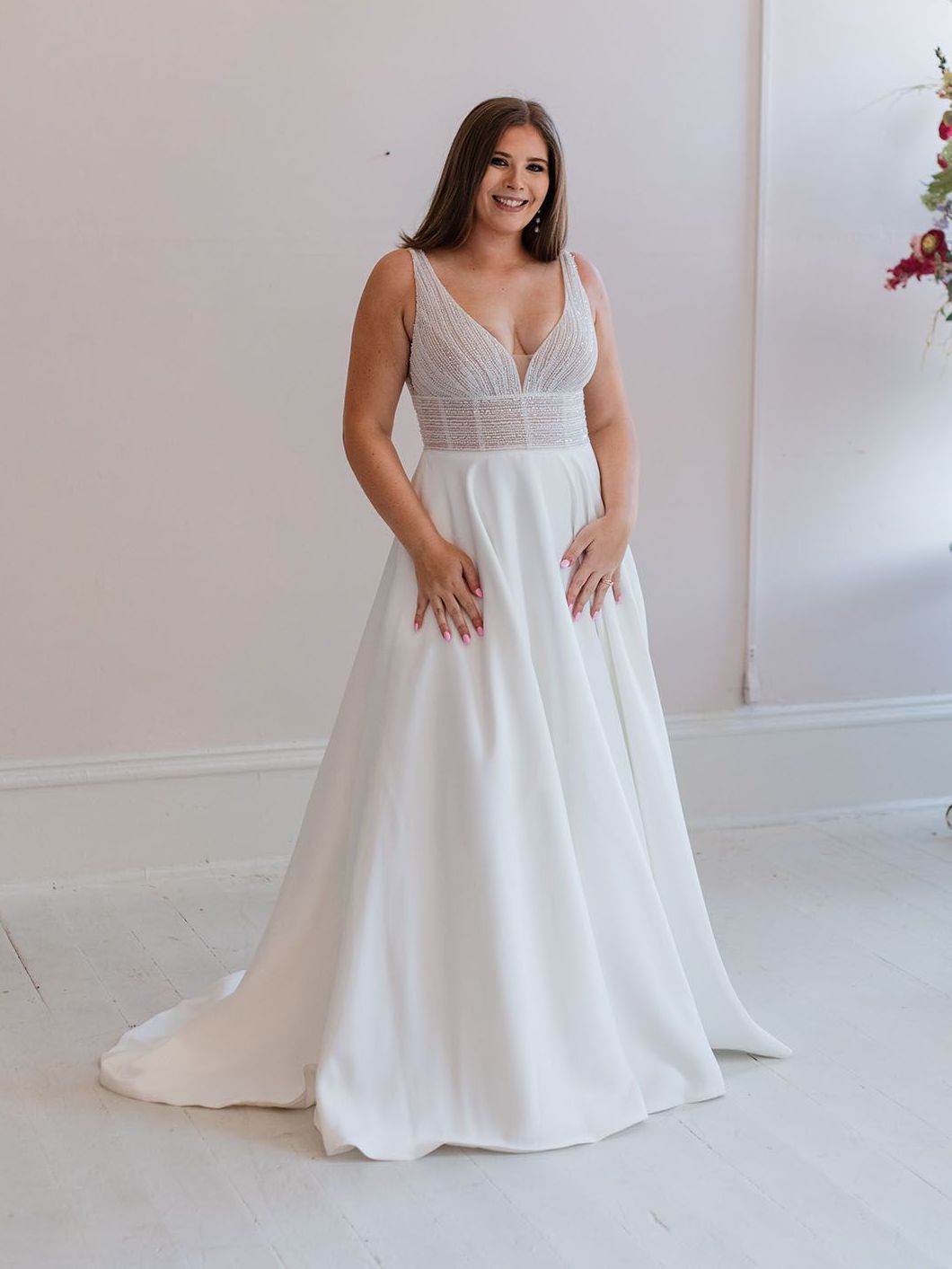 A woman in a white wedding dress is standing in a room.