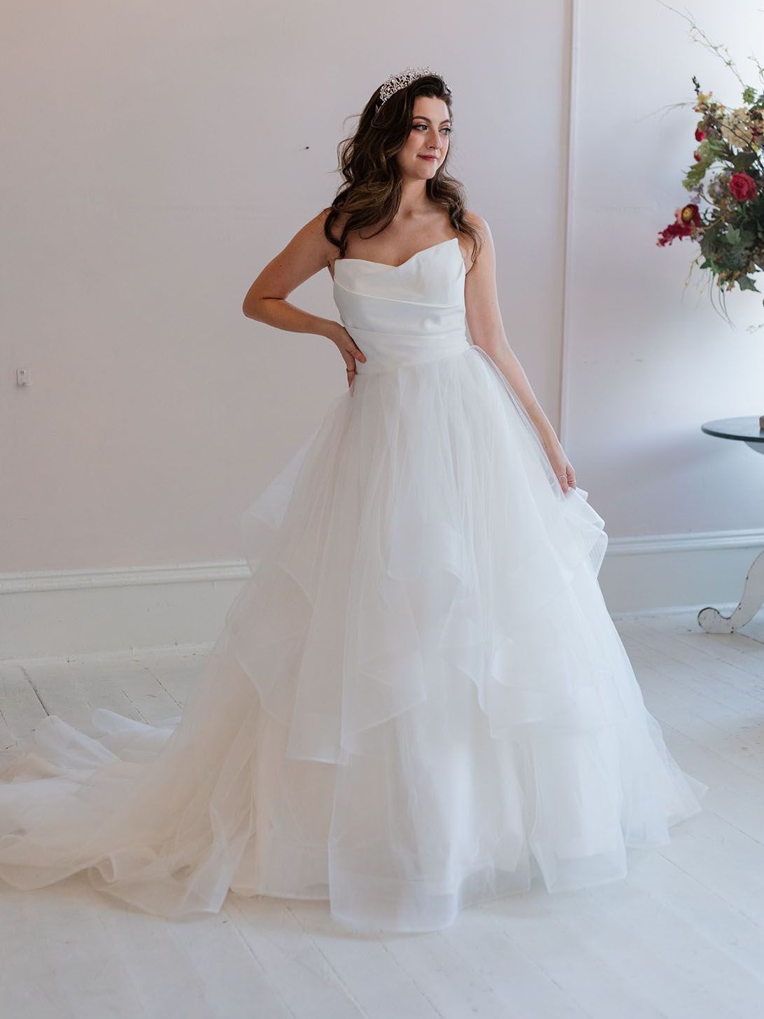 A woman in a white wedding dress is standing in a room.