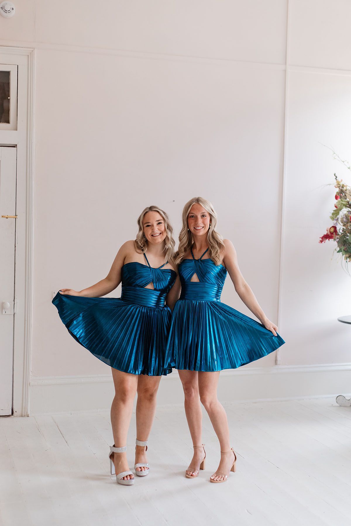 Two women in blue dresses are standing next to each other in a room.