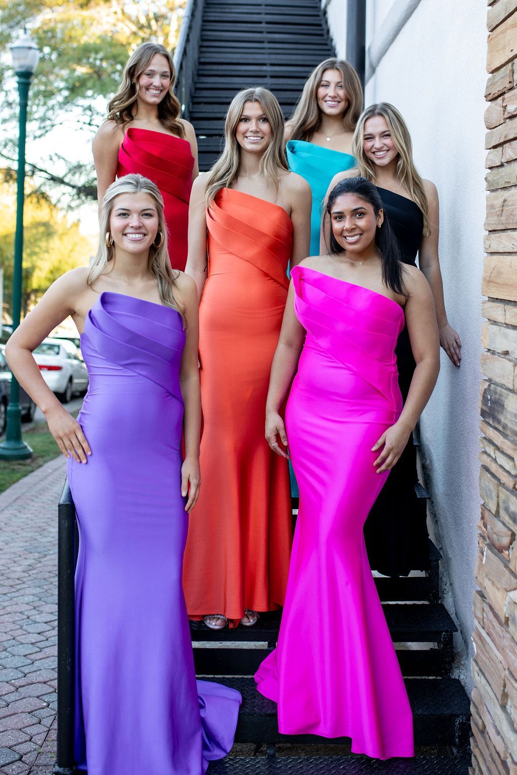 A group of women in colorful dresses are standing on stairs.