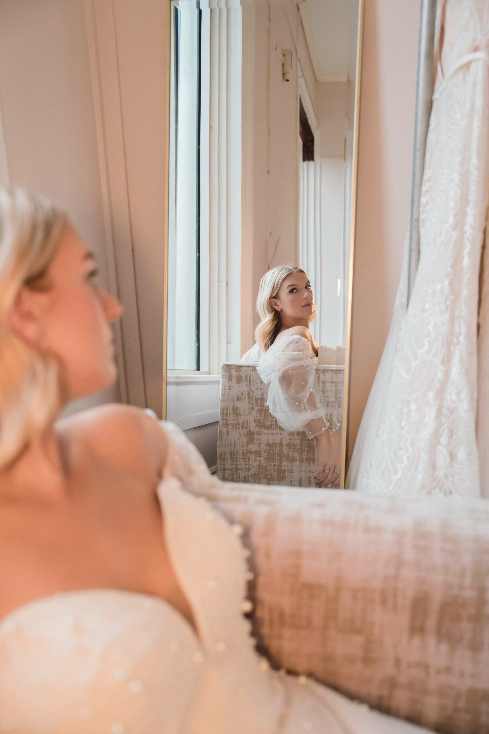 A woman in a wedding dress is looking at her reflection in a mirror.