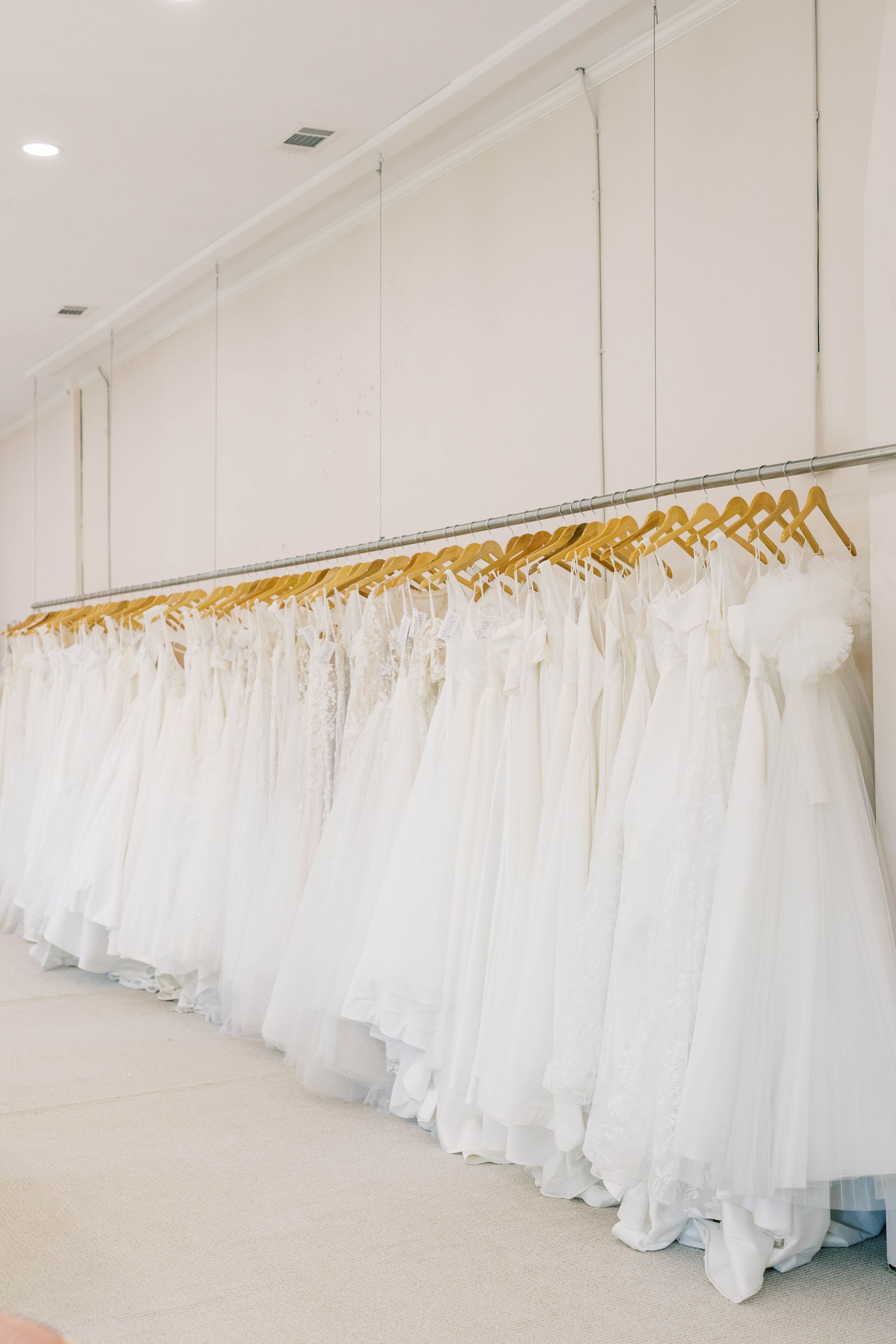 White wedding dresses hanging on a rack in a bridal shop.