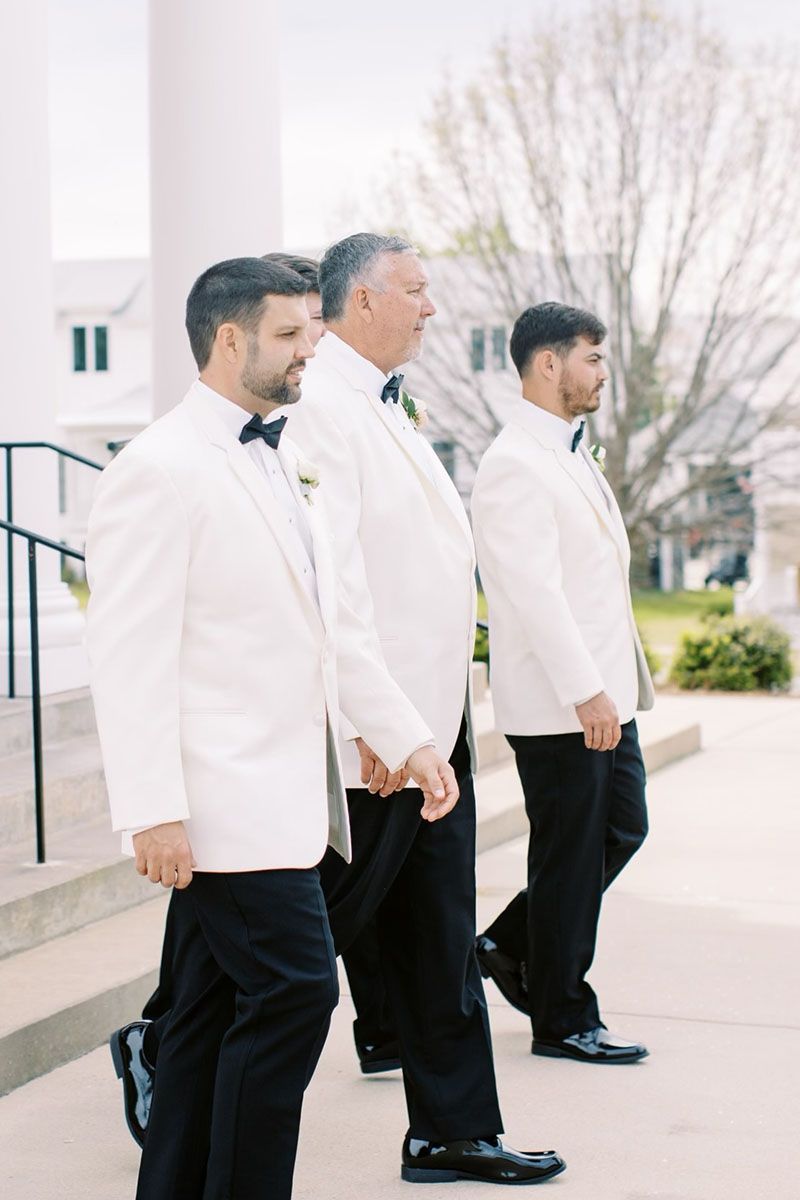 The groom and his groomsmen are walking down the aisle holding hands.