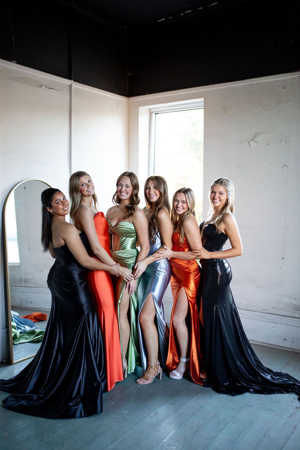 A group of women in long dresses are posing for a picture in a room.