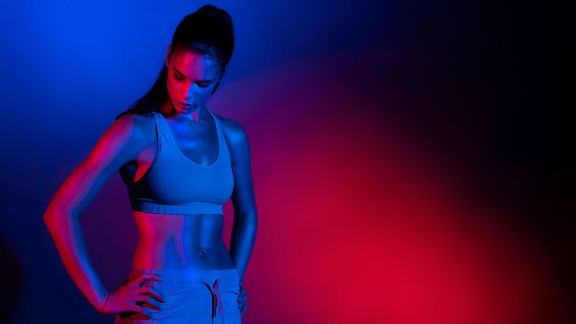 A woman is standing with her hands on her hips in a neon light.