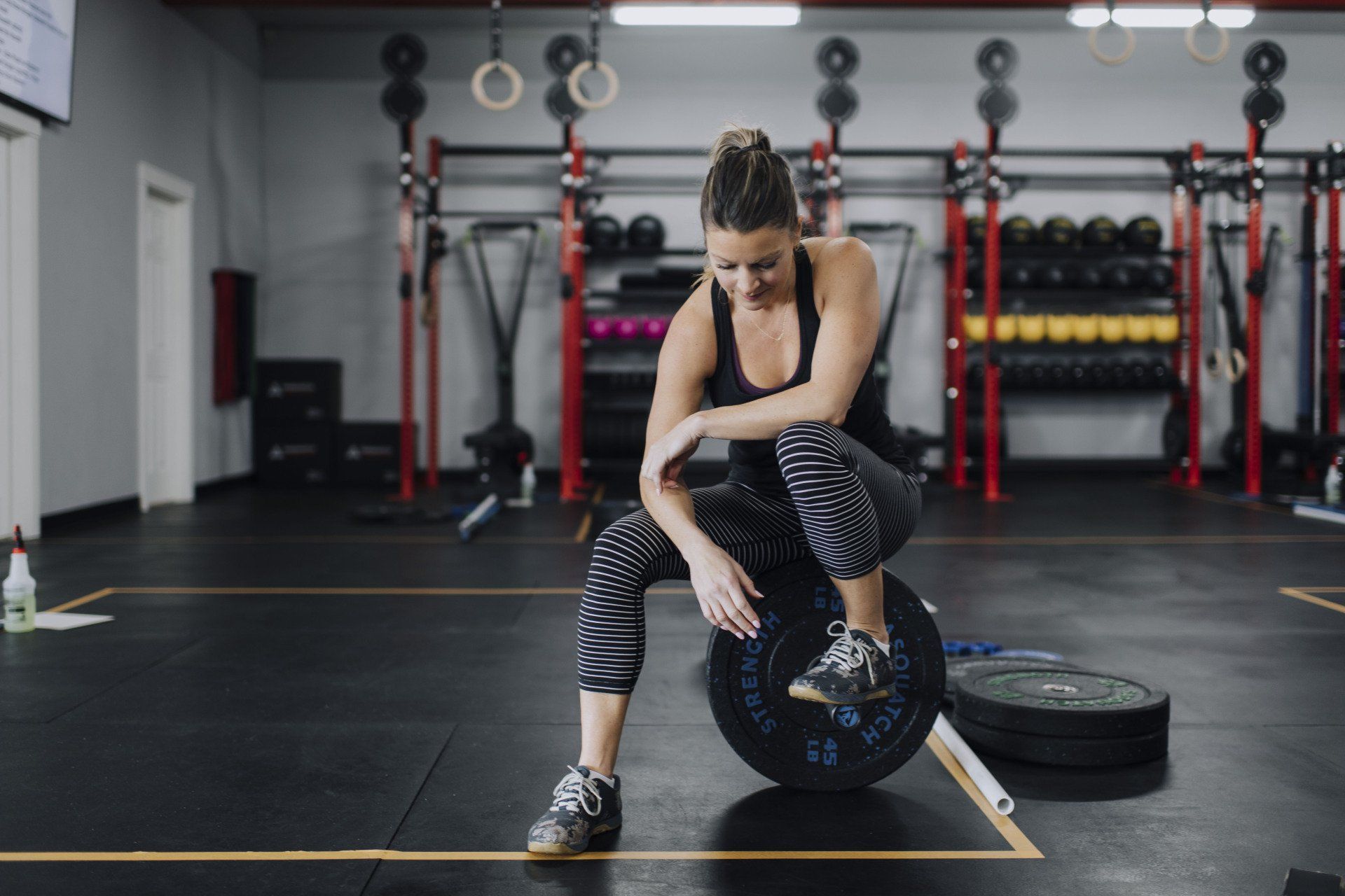 A woman is squatting on a barbell in a gym.