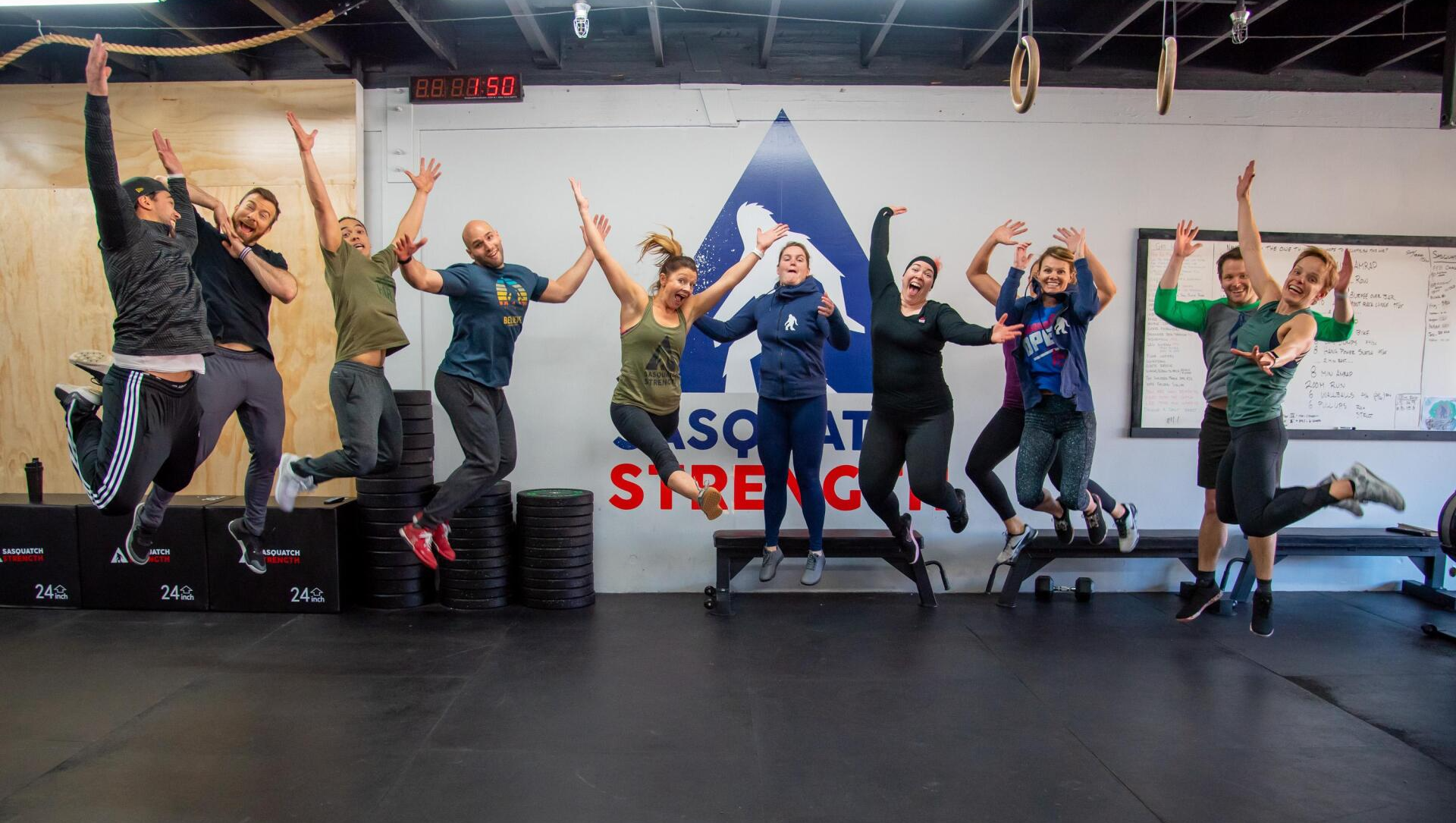 A group of people are jumping in the air in a gym.