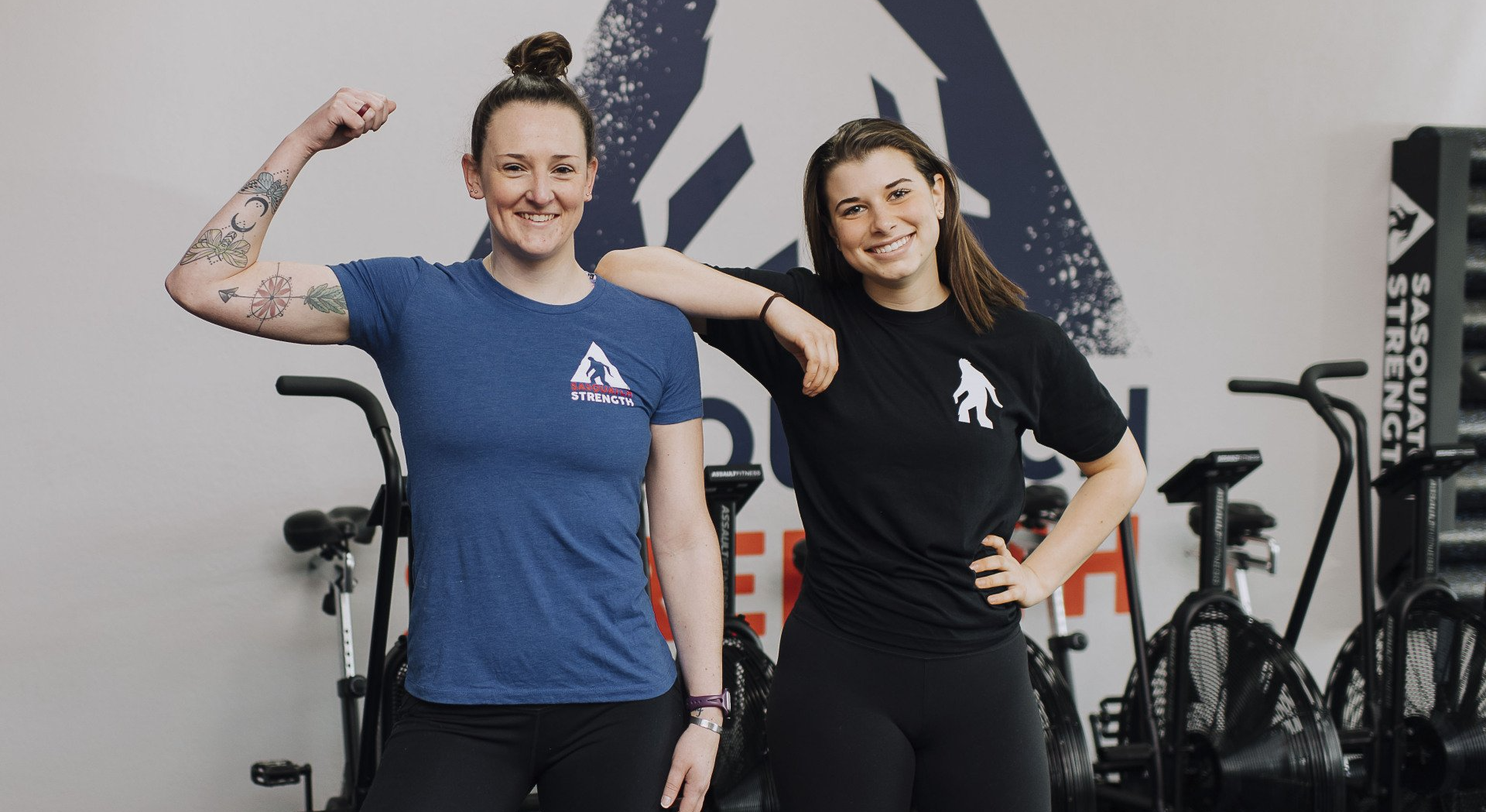 Two women are standing next to each other in a gym.