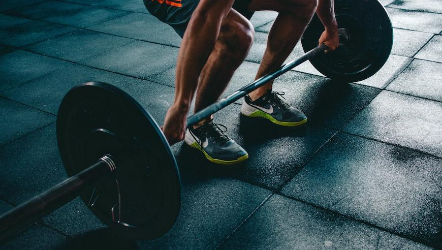 A man is lifting a barbell in a gym.